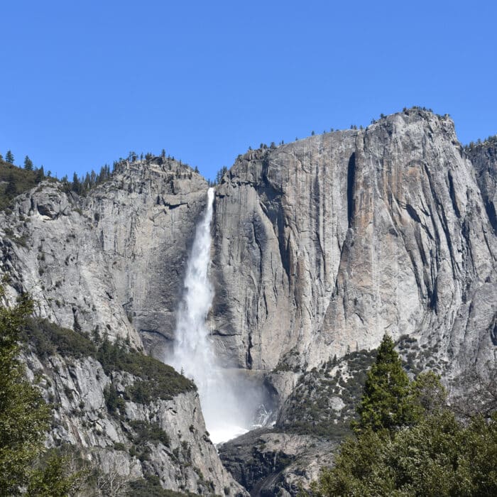 A landscape view of massive granite wall with a waterfall and in Yosemite Valley, California