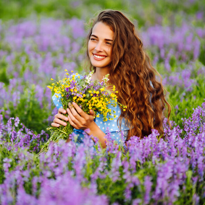 Portrait of beautiful woman in amazing in a blooming field. Nature, vacation, relax and lifestyle.