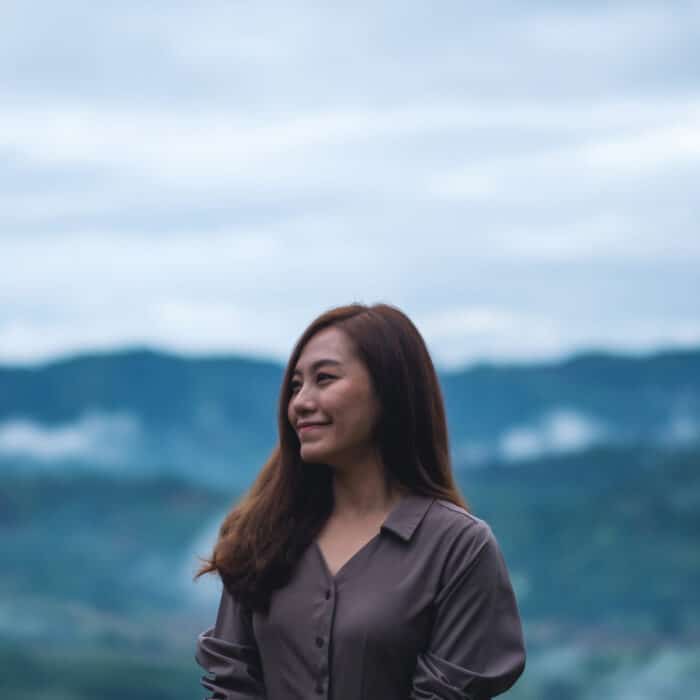 Portrait image of a female traveler with a beautiful foggy mountain and nature view