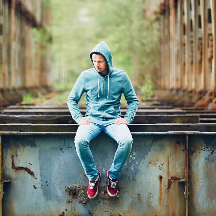 Sad man sitting on the abandoned rusty bridge. Concept for sadness, loneliness and more.