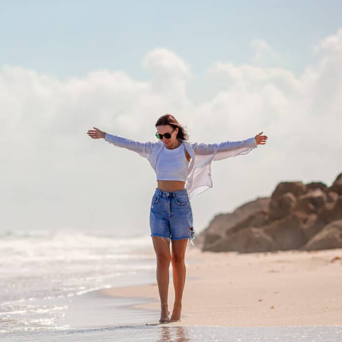 Young happy woman on the beach enjoy her summer vacation. Girl is happy and calm in her stay on the beach