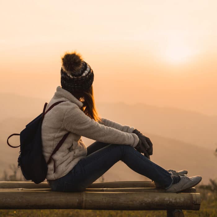 Young woman traveler looking at sunrise over the mountain
