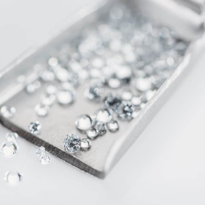 Selective focus of small diamonds on spatula isolated on grey