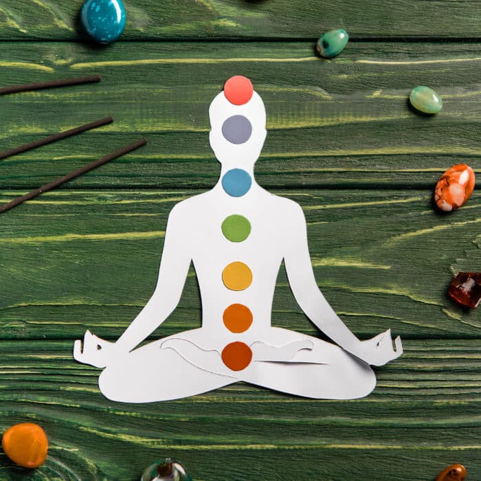 Top view of paper figure in form of person with chakras in lotus pose, aroma sticks and colorful
