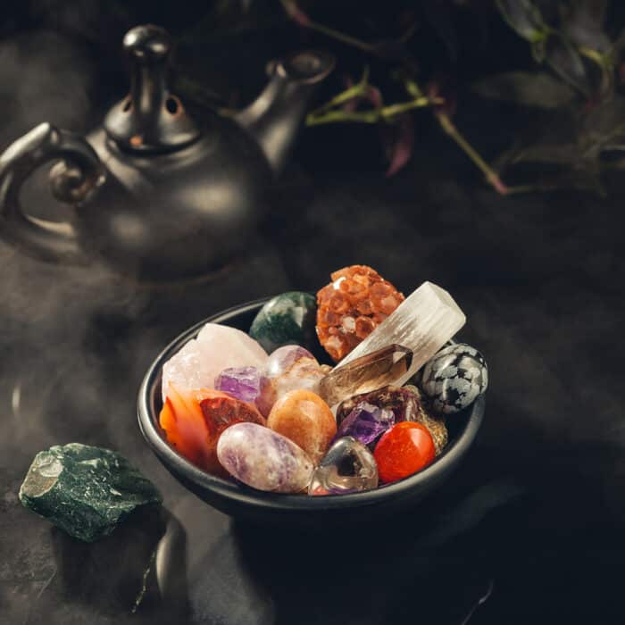 Bunch of Colorful Crystals and Rough Mineral Stones in the Black Bowl Shrouded in a Mystical Mist. Crystal Cleansing Fumigation. Copy Space for Text