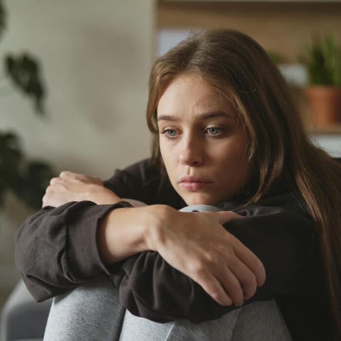 Caucasian sad woman sitting at the sofa with depression