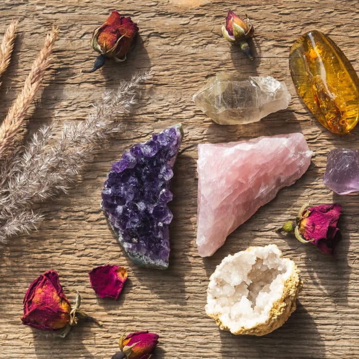 Amethyst druzy, pink quartz, quartz with rutile, fluorite, copal and quartz in geode mineral stones set up on the wooden table with dry flowers. Gemstones for esoteric spiritual practice or witchcraft