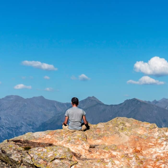 Man meditating in a rocky mountain during a cloudless day