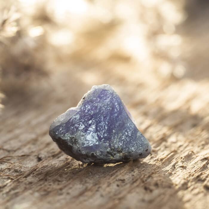 Rough Uncut Blue and Violet Tanzanite Gem on Wooden Background. Tanzanite is the most Valuable Gemstone