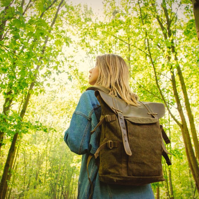 Young woman with backpack in a mixed forest Beskidy in Poland in spring time.