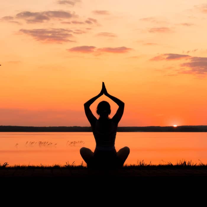 Silhouette of a girl sitting in meditation during sunset, meditation