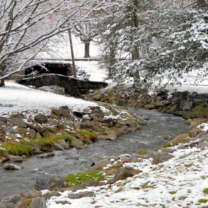 Stone bridge over a creak, running stream, creak snowy landscape