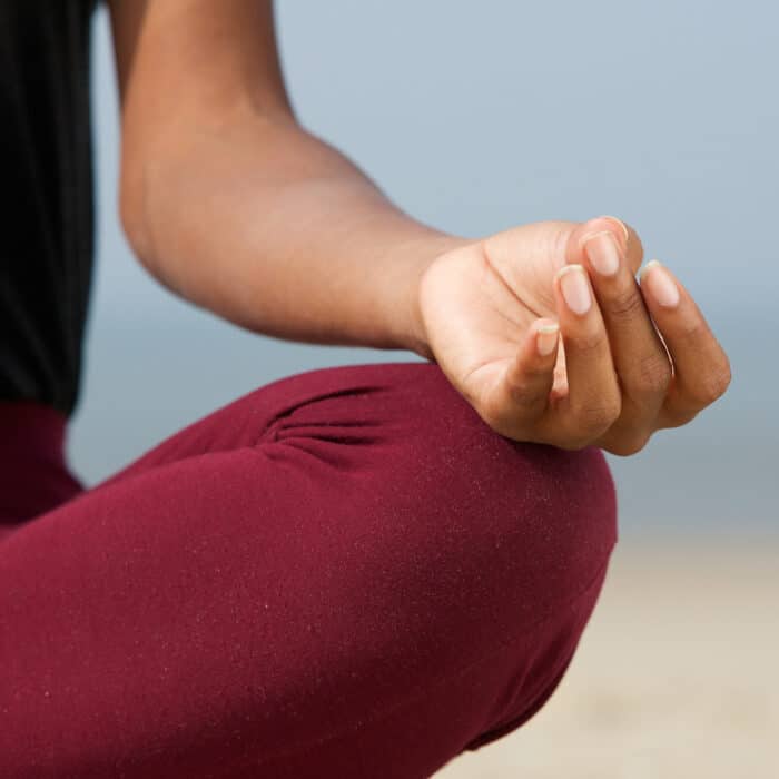 Close up portrait of a young woman in lotus position at the beach