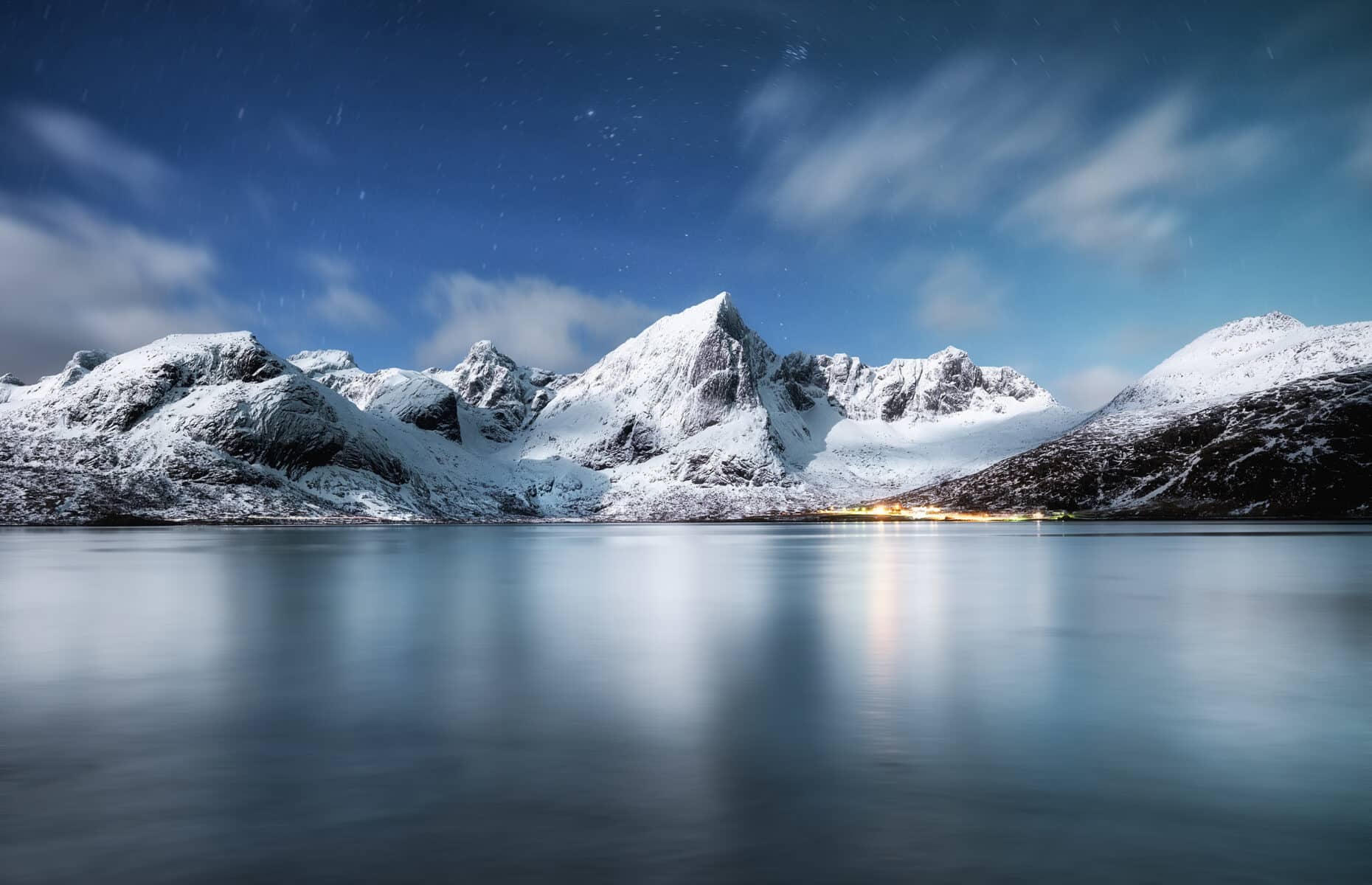 Mountains and reflections on water at night. Winter landscape. The sky with stars and clouds in motion. Nature as a background. Norway - travel