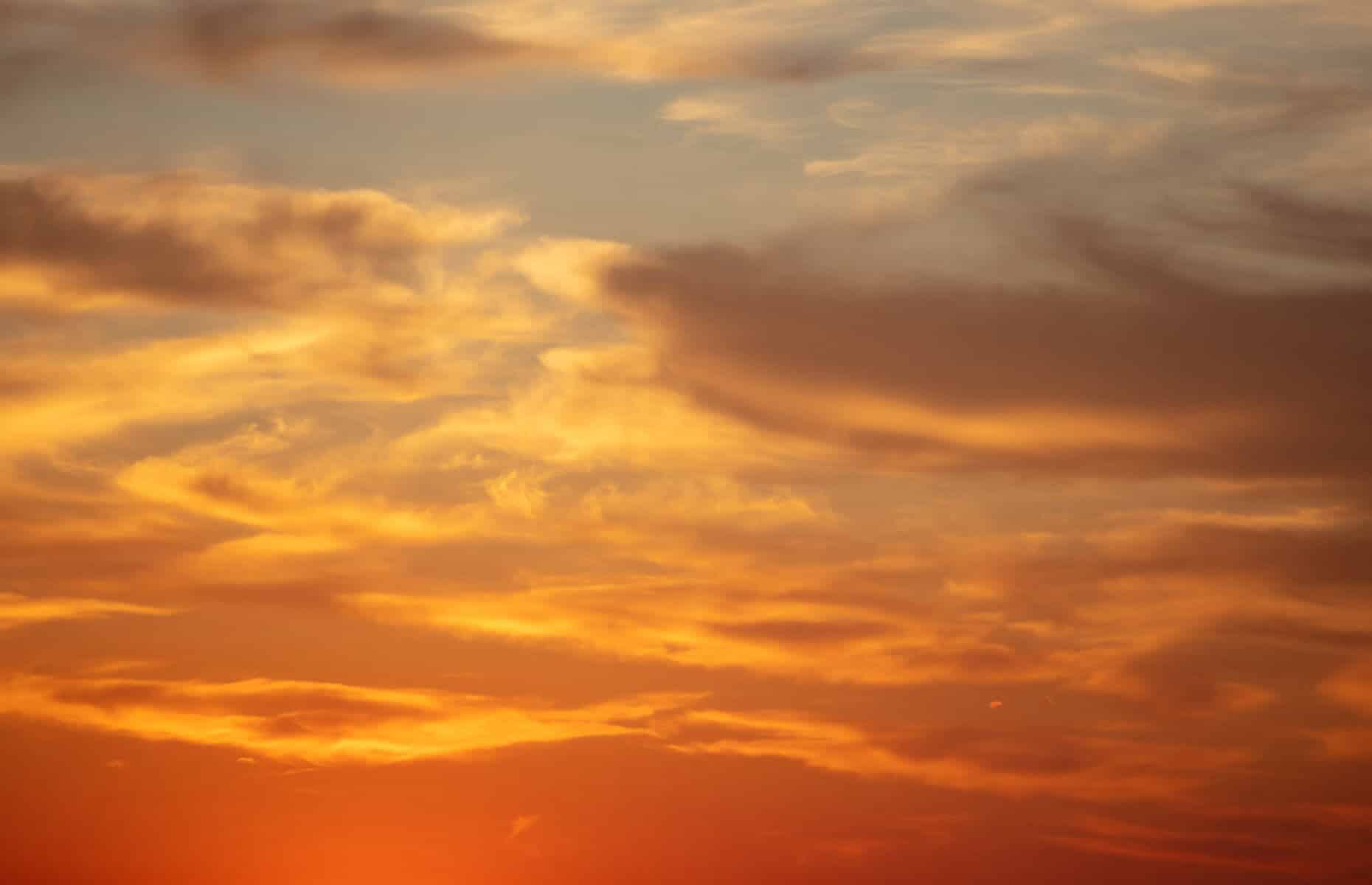 Sunset orange cloudscape background. Dramatic magical sunrise over orange cloudy sky. Twilight, dawn