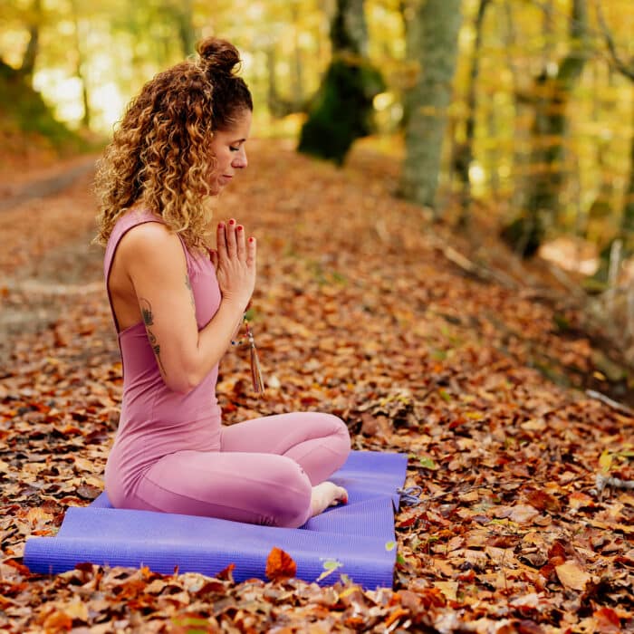 Young woman meditating sitting in a forest.