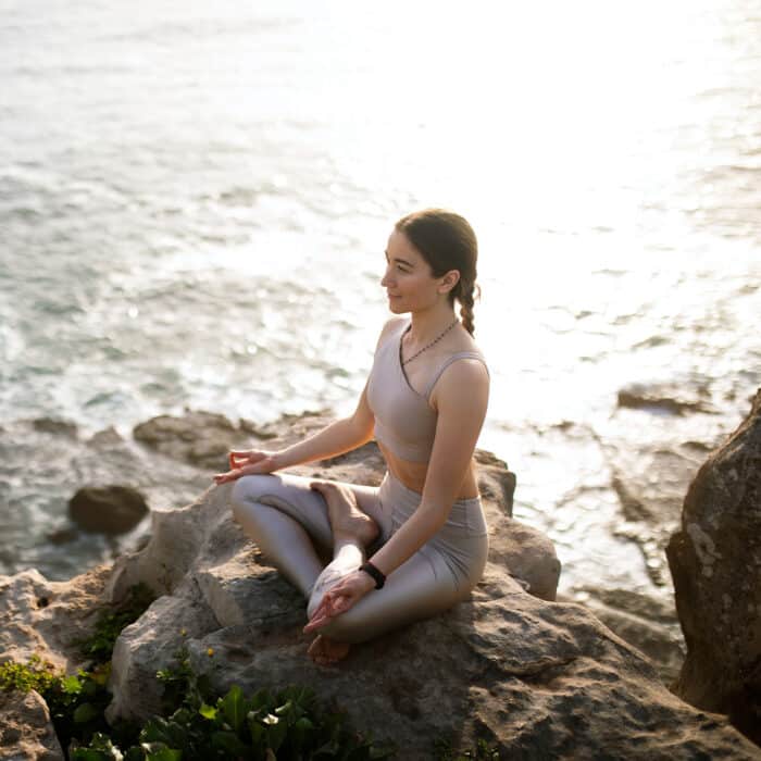 Calm happy slim millennial european lady in sportswear practicing yoga, enjoy workout near sea, outdoor, sun flare. Health care, body care, weight loss, active lifestyle and meditation