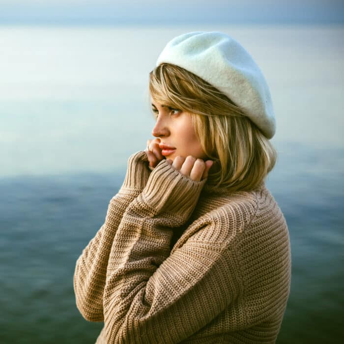 Charming calm portrait of beautiful girl in sweater on sea shore