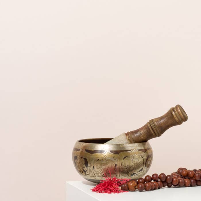 Copper singing bowl and wooden clapper on a white table. Musical instrument for meditation, relaxation, various medical practices related to biorhythms, normalization of mental health