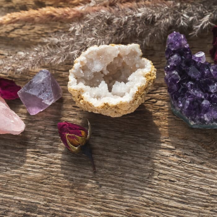 Alternative crystal healing concept. Healing Stones for Wicca Witchcraft Practice Set Up on Wooden Table with Dry Herbs and Flowers. Copy Space from the Bottom of the Composition