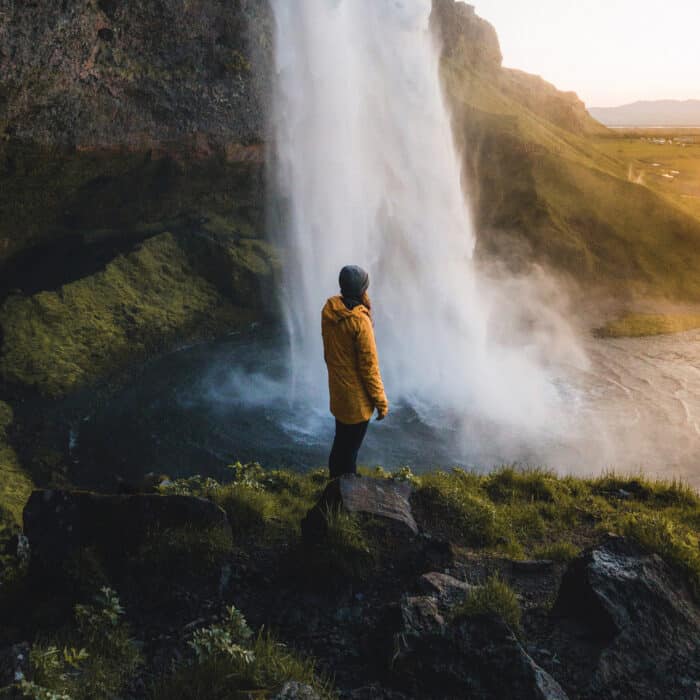 Person standing on rock near waterfalls