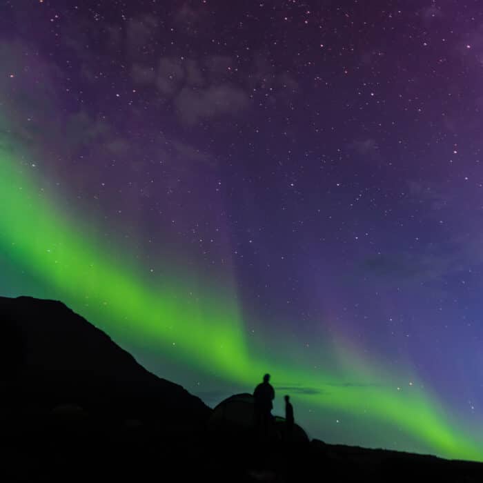 Tourists looking up at Aurora Borealis, Narsaq, Vestgronland, Greenland