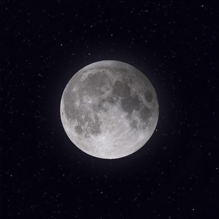 A vertical grayscale of the full moon with stars shining in the background