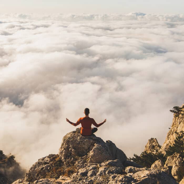 Yoga meditation with mountain view over low clouds