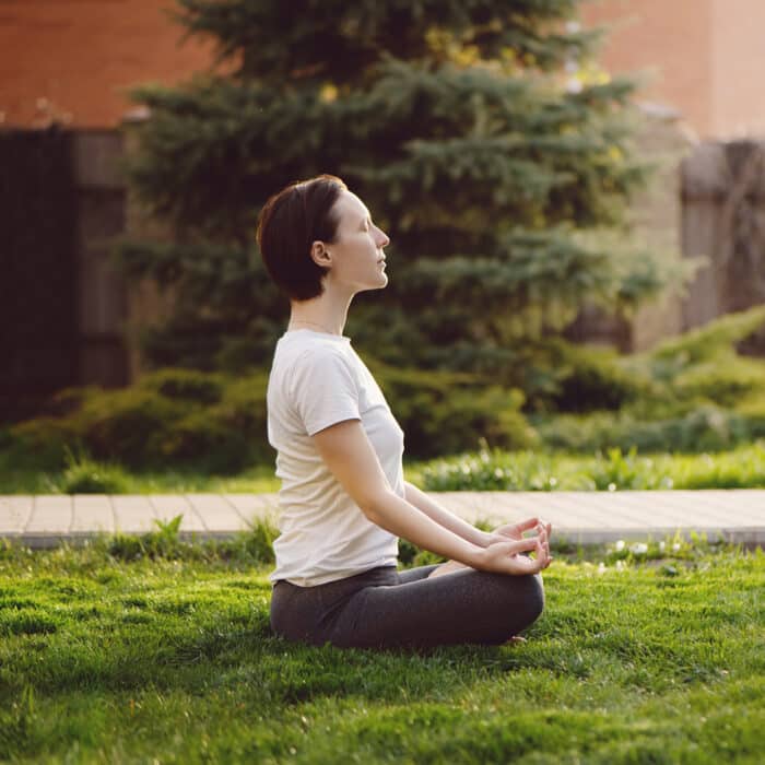 Young woman practicing meditation in the backyard