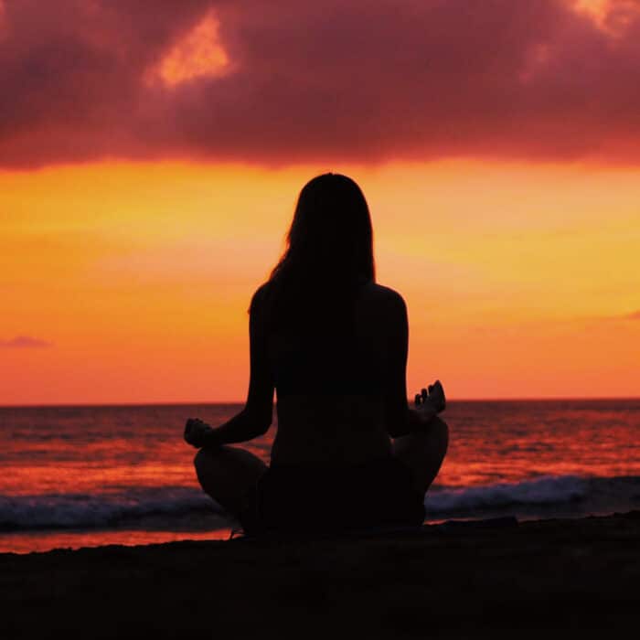 Woman meditating during sunset at the beach