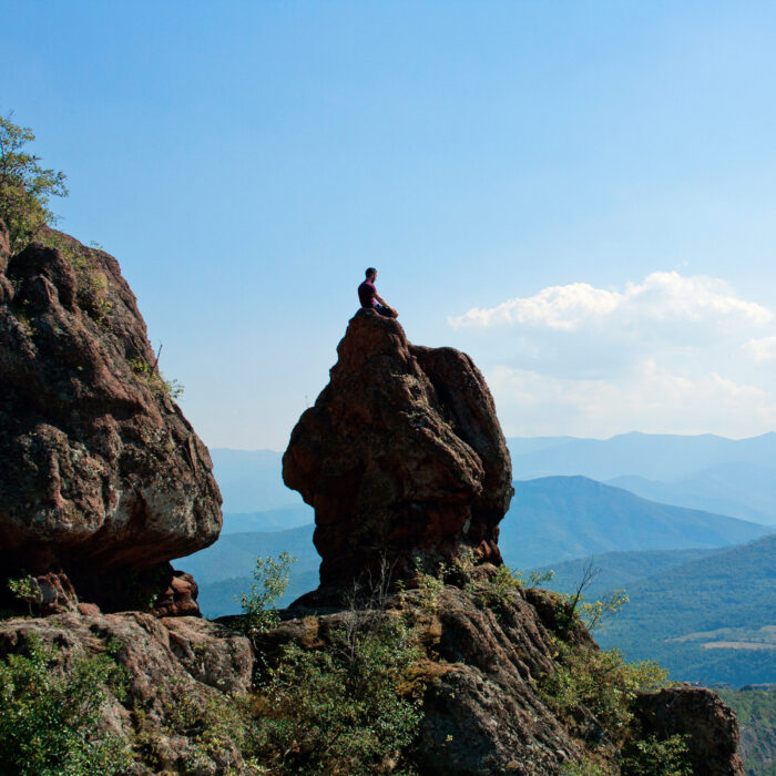 A guy meditating on a big rock