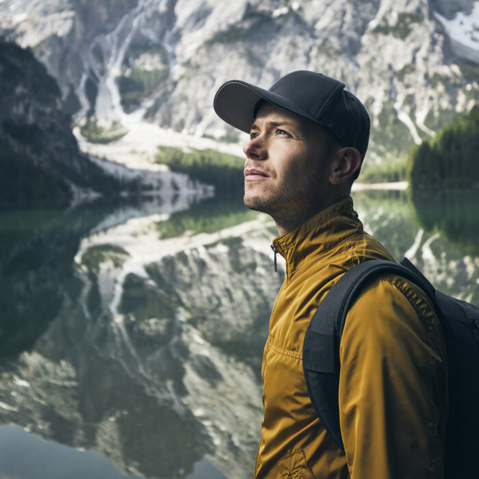 Young man (tourist) in nature. Mountains refelection in Lake Braies, Italy.