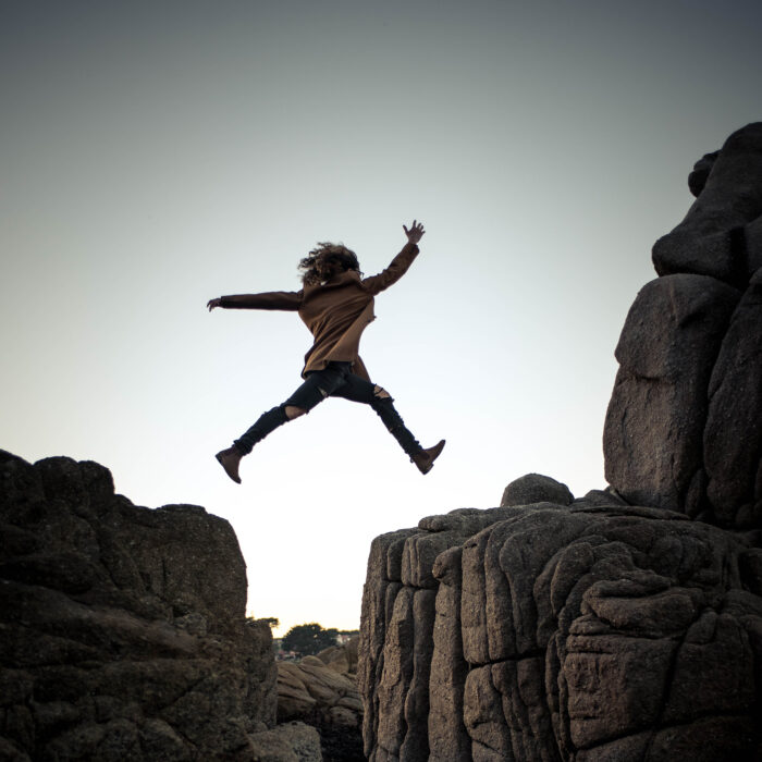 Person jumping between rocks