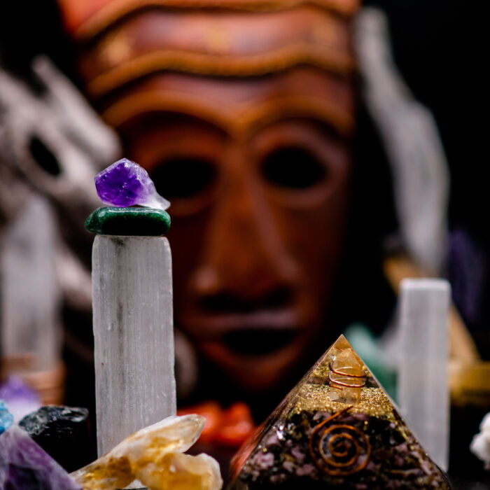 A composition of crystal stones and a mystique mask in the background- the concept of crystal healing and a spiritual energy